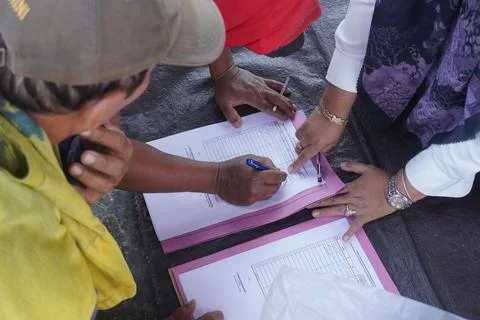 A group of people pointing at a paper while others are writing Stockfoto's