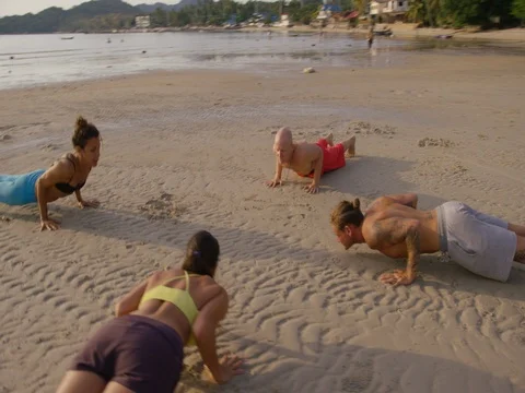 Group of people practicing cobra pose on the beach during sunset Stock Footage 75291069
