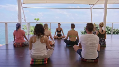 Group of people practicing lotus position in gazebo near the sea Stock Footage 74771988