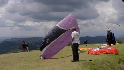 Group of people preparing para glider equipment as lone pilot jumps off Stock-Footage 102064777