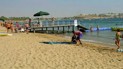 Group of people preparing props on a sunny sandy beach near the sea resort Stock-Footage 338332529