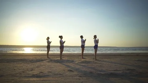 Group of people profile do yoga poses namaste sundown seaside rapid slow motion  Stock Footage 78753274