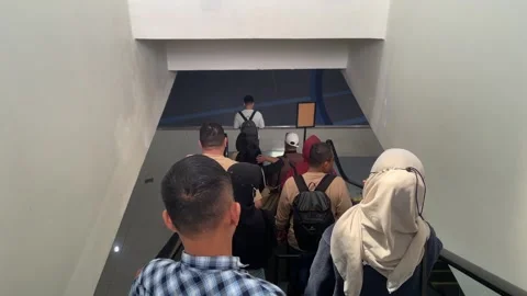 A group of people riding down an escalator inside a building. 库存影片 333836766