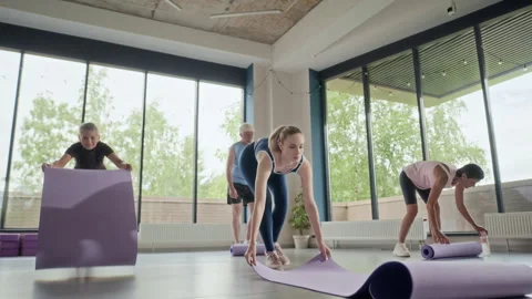 Group of People Rolling out Yoga Mats in Fitness Studio Stock Footage 339860192