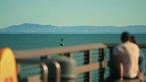 Group of people siting on a bench enjoying the views of the Pacific Ocean Stock Footage 341665253