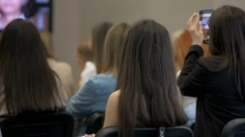A group of people sitting in a lecture hall watching a presentation on TV Video stock 314979247