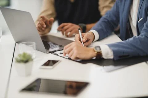 A group of people sitting at a table using a laptop in work Stock Photos
