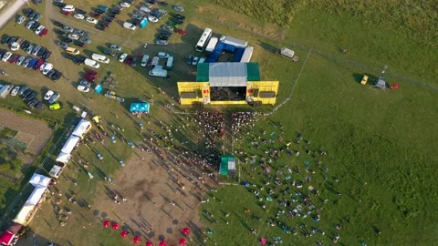 Group of people standing in front of a stage in a field at a concert. Stock Footage 158609155