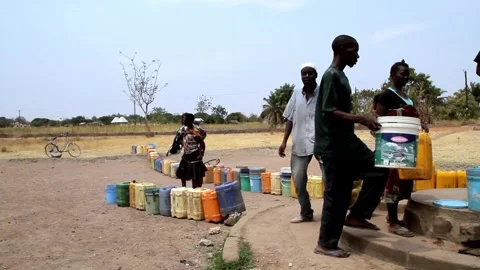 A group of people standing in a long queue with various plastic containers and Stockbeeldmateriaal 345835204