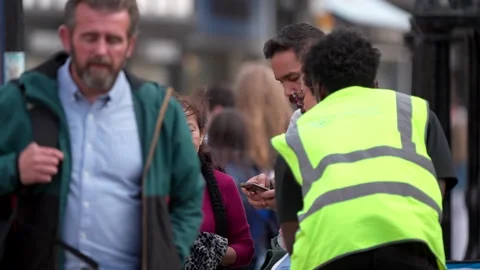 A group of people talking and using a phone on a public street Stock Footage 283546915