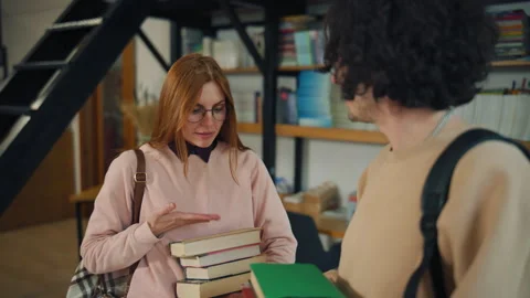 Group of people talking in a library while holding books and discussing reading  Stock Footage 337137654