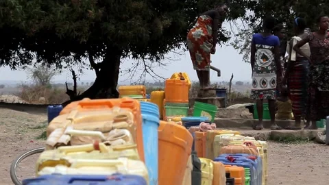 A group of people waiting in a long queue with colorful plastic containers to Video stock 345835193