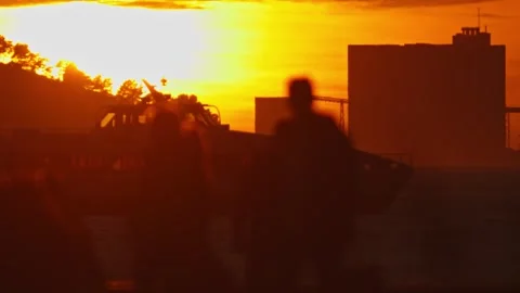 A Group of People Walking Down a Street at Sunset Stock Footage 257079572