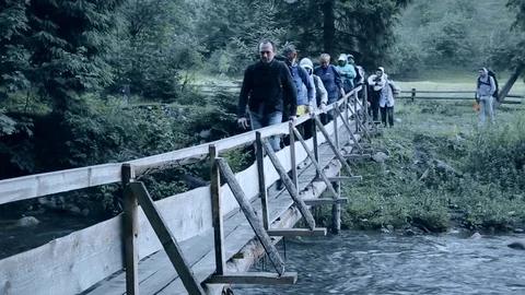 Group of people walking one after another across the bridge across the river Stock Footage 83280292