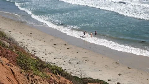 A group of people walking on a sandy beach next to the ocean Stock Footage 155584343