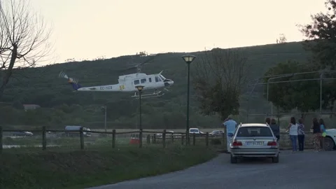 Group of people watching closely a helicopter picking up water from lake Stock Footage 139616853
