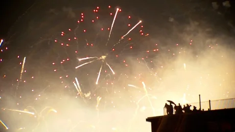 Group of people watching massive new year fireworks from a building rooftop Stock Footage 100483355