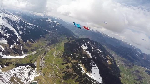 Group of people in wingsuits flying high above ground and doing tricks, Aspen Stock Footage 129131996