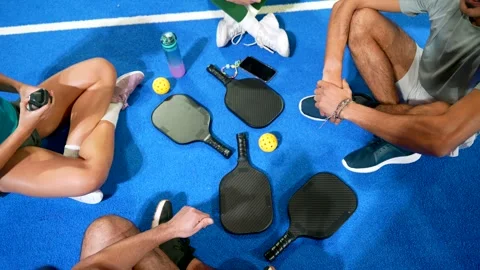 Group of pickleball players resting on blue court Stock Footage 329549616