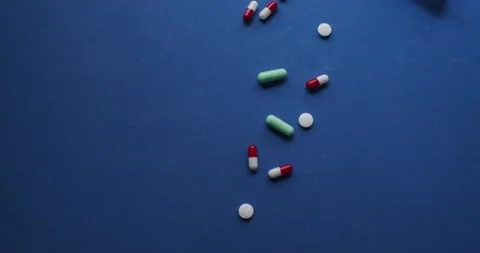 Group of pills of different sizes and colors on a blue background. Stock Footage 130776157