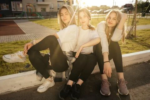 Group portrait of three happy young girls sitting and hugging, laughing and Stock Photos