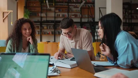 Group of positive multicultural students studying and talking in library Stock Footage 250339498