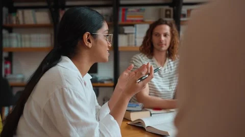 Group of positive multinational students studying and talking in library Stock Footage 250339658