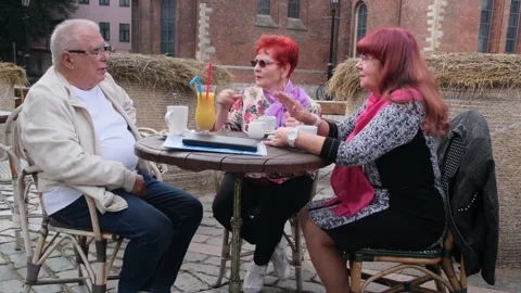 Group of positive pensioners talks at table in street cafe Stock Footage 139797457