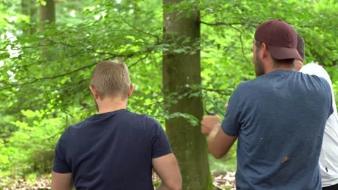 Group practicing slingshot shooting in forest during outdoor survival training 動画素材 330970345