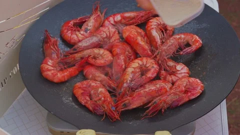 Group of prawns frying in a flat cast iron pan outdoors Stock Footage 231586669