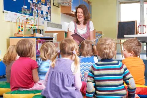 Group Of Pre School Children Listening To Teacher Reading Story Stock Photos