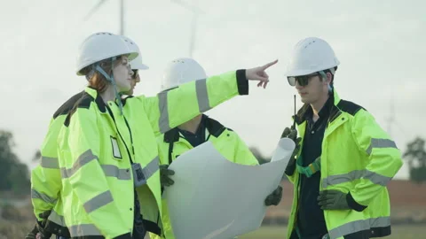 Group of professional engineers in safety gear reviewing a project blueprint Stock Footage 325552367