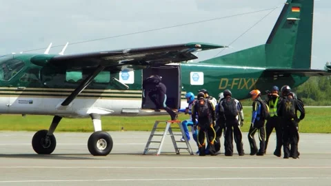 Group of professional skydivers moving into the green aircraft before it Stock Footage 159781000
