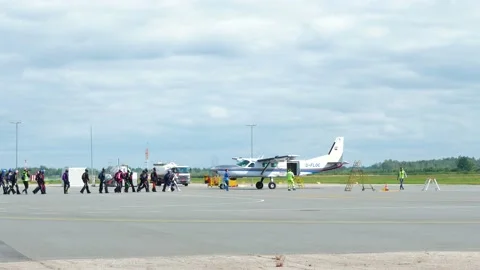 Group of professional skydivers moving towards the white aircraft before Stock Footage 159780120