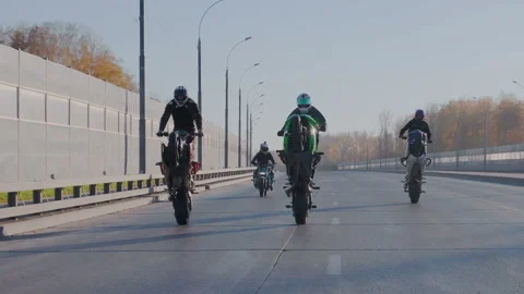 A group of professional stunt drivers simultaneously ride on the rear wheel at Stock Footage 105011972