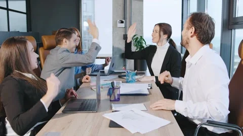 A group of professionals engage in a high-five during a meeting in a business Vídeos de archivo 326561529