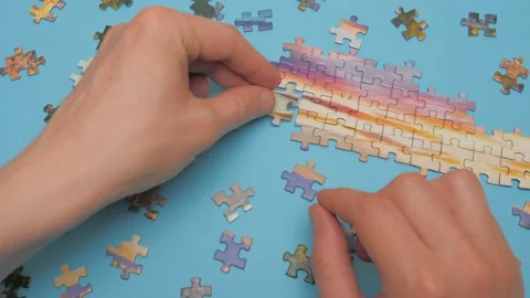 A group of puzzles, hands on blue table background. Puzzle game, preschool Stock Footage 132927947