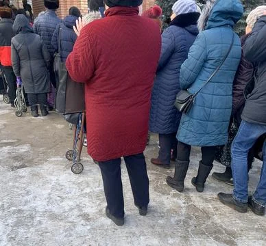 A group, a queue of people with handcarts in the cold season. Stock Photos
