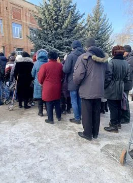 A group, a queue of people with handcarts in the cold season. Stock Photos
