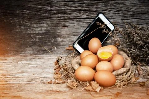 Group of raw eggs put in front of moblie phone,on wooden timber board,warm li Foto stock