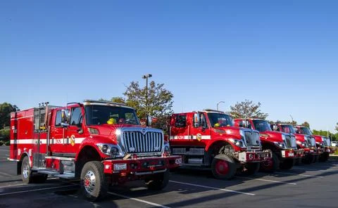 A group of red Cal Fire fire engine trucks in parking lot. First responders Stock Photos