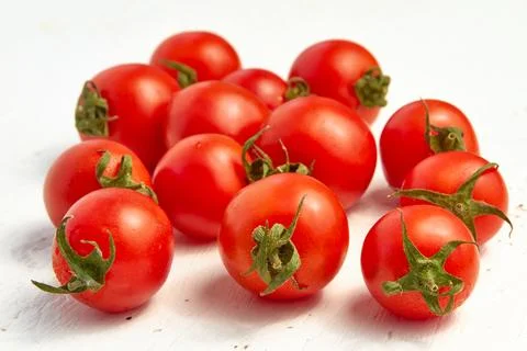 Group of red cherry tomatoes, ripe organic tomatoes on a light wooden backg.. Stock Photos