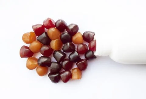 Group of red, orange and purple multivitamin gummies with the bottle isolated on Stock Photos