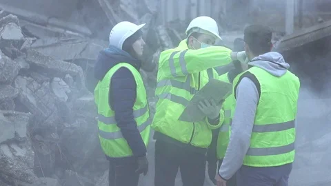 Group of rescue workers examine the map after an earthquake or hurricane Stock Footage 98035559