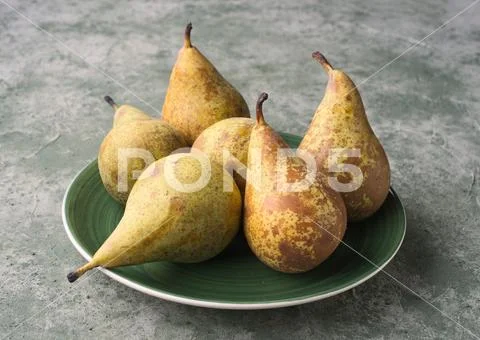 Group of ripe pears in green porcelain dish on green marbling background Stock Photos