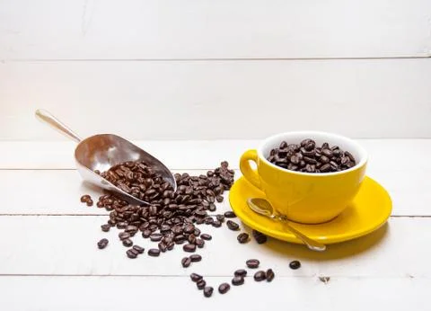 The group of roasted coffee beans put in yellow ceramic cup and staliness spo Stock Photos