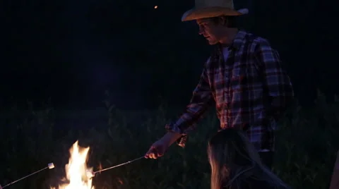 Group roasts marshmallows over fire at dawn Stock Footage 56564378
