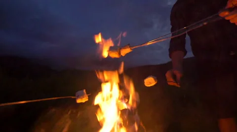 Group roasts marshmallows over fire dolly out Video stock 56564921