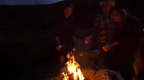 Group roasts marshmallows over fire pan around Stock Footage 56565319