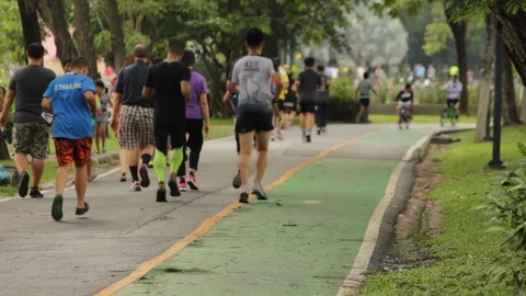 A group running in a park, with cyclist in the background Stock Footage 91212177